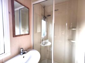 A bathroom with a mirror, sink, and shower at Snowdonia Sunbeach Holiday Sea and Mountain view, Llwyngwril