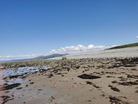 A beach with rocks and seaweed at Snowdonia Sunbeach Holiday Sea and Mountain view in Llwyngwril