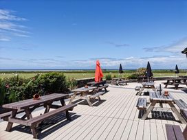 An outdoor seating area with tables and umbrellas at Snowdonia Sunbeach Holiday Sea and Mountain view, Llwyngwril