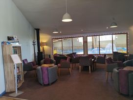 A lounge area with armchairs and a bookshelf at Snowdonia Sunbeach Holiday Sea and Mountain view, Llwyngwril