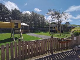 A playground with a slide and swings at Snowdonia Sunbeach Holiday Sea and Mountain view in Llwyngwril