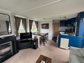 A living room with a television, sofa, and dining area at No 38 Heilan Hoose at Three Lochs Holiday Park near Newton Stewart