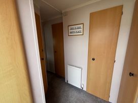 A hallway with multiple doors and a sign at No 38 Heilan Hoose at Three Lochs Newton Stewart