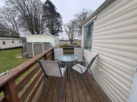 A deck area with table and chairs at No 38 Heilan Hoose at Three Lochs Holiday Park near Newton Stewart