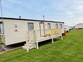 A mobile home with a deck and yellow chairs at Seaside Tranquility Retreat in Clacton