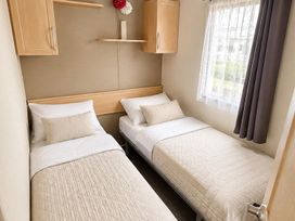 A bedroom with two single beds and a shelf at Seaside Tranquility Retreat in Clacton