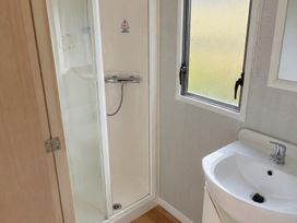 A bathroom with a shower, sink, and window at Seaside Tranquility Retreat in Clacton