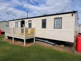 A mobile home with a deck and yellow chairs at Seaside Tranquility Retreat in Clacton