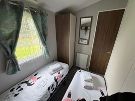 A bedroom with beds and a wardrobe at Wl34 Caravan Haggerston Castle Private Decking Haggerston
