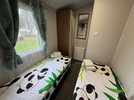 A bedroom with two beds, a wardrobe, and a window at Wl34 Caravan Haggerston Castle Private Decking Haggerston