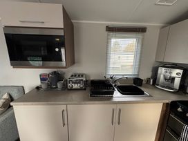 A kitchen with microwave toaster and coffee machine at Wl34 Caravan Haggerston Castle Private Decking