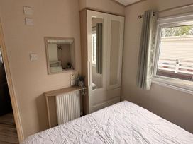 A bedroom with a mirror and wardrobe at Caravan - Sleeps 8 - Parking Northampton