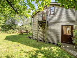 A wooden structure with a balcony and garden seating area at 3-Bed Barn Eco-Lodge on the Tarka trail East Yarde near Great Torrington