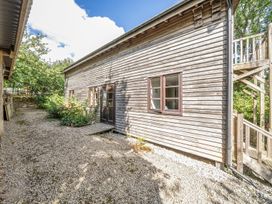 A wooden building with gravel and plants at 3-Bed Barn Eco-Lodge on the Tarka trail East Yarde near Great Torrington