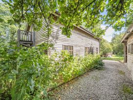 A building with a balcony and plants surrounding a pathway at 3-Bed Barn Eco-Lodge on the Tarka trail, East Yarde near Great Torrington
