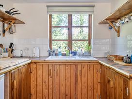 A kitchen with a sink and shelves at 3-Bed Barn Eco-Lodge on the Tarka trail, East Yarde near Great Torrington