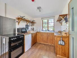 A kitchen with stove, refrigerator, and sink at 3-Bed Barn Eco-Lodge on the Tarka trail East Yarde near Great Torrington