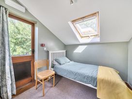 A bedroom with a single bed and chair at 3-Bed Barn Eco-Lodge on the Tarka trail, East Yarde near Great Torrington