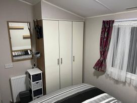 A bedroom with a bed, wardrobe, and mirror at Seafront Caravan - Golden Sands - 6 Berth by Your Away Stays in Kinmel Bay