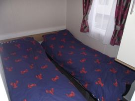 A bedroom with two beds and a window at Seafront Caravan - Golden Sands - 6 Berth by Your Away Stays, Kinmel Bay