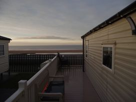 An outdoor area with a caravan and a view of the sea at Seafront Caravan - Golden Sands - 6 Berth by Your Away Stays in Kinmel Bay