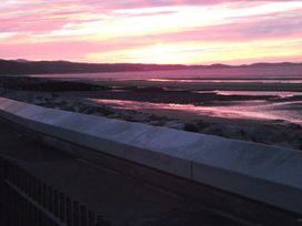 A sunset over water with rocks at Seafront Caravan - Golden Sands - 6 Berth by Your Away Stays Kinmel Bay