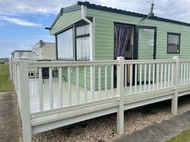 A caravan with a deck and railing at 4 Bed Lodge Sleeps 8 - Pets & WiFi Free Parking in Ingoldmells