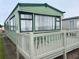A static caravan with decking and a table in an outdoor area at 4 Bed Lodge Sleeps 8 - Pets & WiFi Free Parking in Ingoldmells