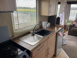 A kitchen with a sink, stove, and refrigerator at 4 Bed Lodge Sleeps 8 - Pets & WiFi Free Parking in Ingoldmells
