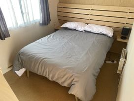A bedroom with a bed and lamp at 4 Bed Lodge Sleeps 8 - Pets & WiFi Free Parking in Ingoldmells