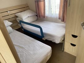 A bedroom with two beds and a wardrobe at 4 Bed Lodge Sleeps 8 - Pets & WiFi Free Parking in Ingoldmells
