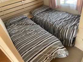 A bedroom with two beds and striped bedding at 4 Bed Lodge Sleeps 8 - Pets & WiFi Free Parking in Ingoldmells
