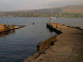 A dock with a boat on the water at Apartment Sleeps 2 with Parking, Pets Welcome in Watermillock near Pooley Bridge