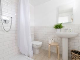 A bathroom with a shower, sink, toilet, and stool at Simple Coastal Luxury near Southwold