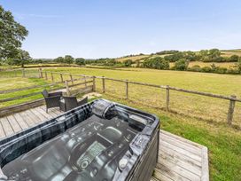 An outdoor space with a hot tub and chairs overlooking a field at The Shippon, Breathtaking Views, Private Hot Tub in Winkleigh