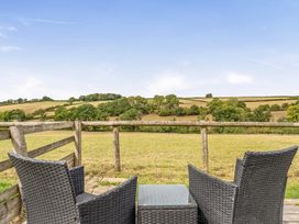 A seating area with chairs and a table overlooking a field at The Shippon, Breathtaking Views, Private Hot Tub in Winkleigh