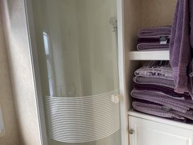 A shower with towels on a shelf at Chalet Sleeps 4 Near Cymyran Beach in Caergeiliog