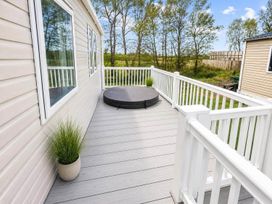 A deck with a hot tub cover and planters at Tattershall Lakes - Hot Tub - Sleeps 6 - Pets in Tattershall