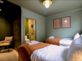 A bedroom with two beds, a chair, and a bathroom at 2 Bedroom Apartment Sleeps 3 - Garden - Pets, Carbis Bay