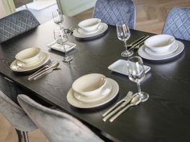 A dining table set with dinner plates and glassware at 2 Bedroom Apartment Sleeps 3 Garden Pets in Carbis Bay