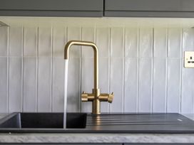 A kitchen sink with a golden faucet and running water at 2 Bedroom Apartment Sleeps 3 Garden Pets Carbis Bay