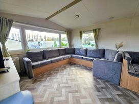 A living room with a large sofa and windows at Static Caravan 3 Bed Sleeps 8 Dog Friendly Parking Northampton