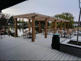 An outdoor area with wooden pergola tables and chairs at Static Caravan 3 Bed Sleeps 8 Dog Friendly Parking Northampton