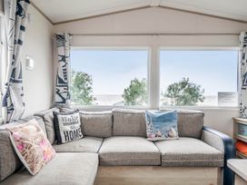 A living room with a sofa and windows overlooking the sea at Cabin - Sleeps 4 - Pets Ok - Balcony - Parking Haven Park, Doniford Bay near Watchet