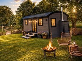 A shepherd hut with a fire pit and outdoor chairs at Peaceful Shepherd Hut near Clovelly