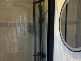 A shower featuring a shower head and a circular mirror at Peaceful Shepherd Hut near Clovelly Buckland Brewer near Great Torrington