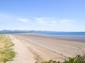 A beach with vehicles and mountains in the background at Ty Gwyn Borth-y-gest House Sleeps 5 Garden Parking Borth-Y-Gest