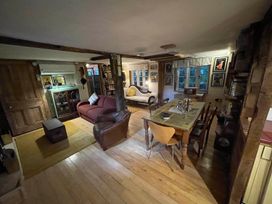 A living room with a sofa, armchair, table, and chairs at The Old Barn in Bovey Tracey
