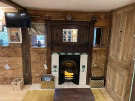 A living room with a fireplace and television at The Old Barn in Bovey Tracey