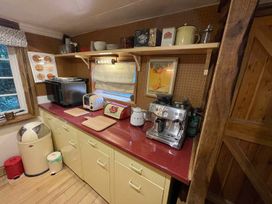 A kitchen with appliances and shelves at The Old Barn in Bovey Tracey